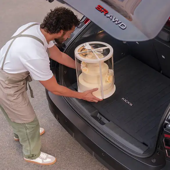 Man putting cake in the trunk of a nissan
