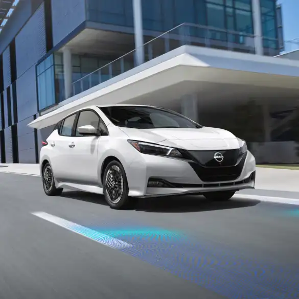 White Nissan Sedan driving on street