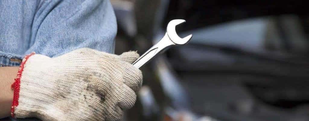 Mechanic wearing gloves and holding a wrench