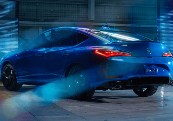 Blue 2026 Acura Integra rear three-quarter view with dramatic studio lighting