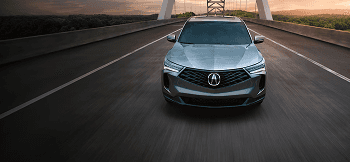 2026 Acura RDX gray front view driving on a bridge at sunset