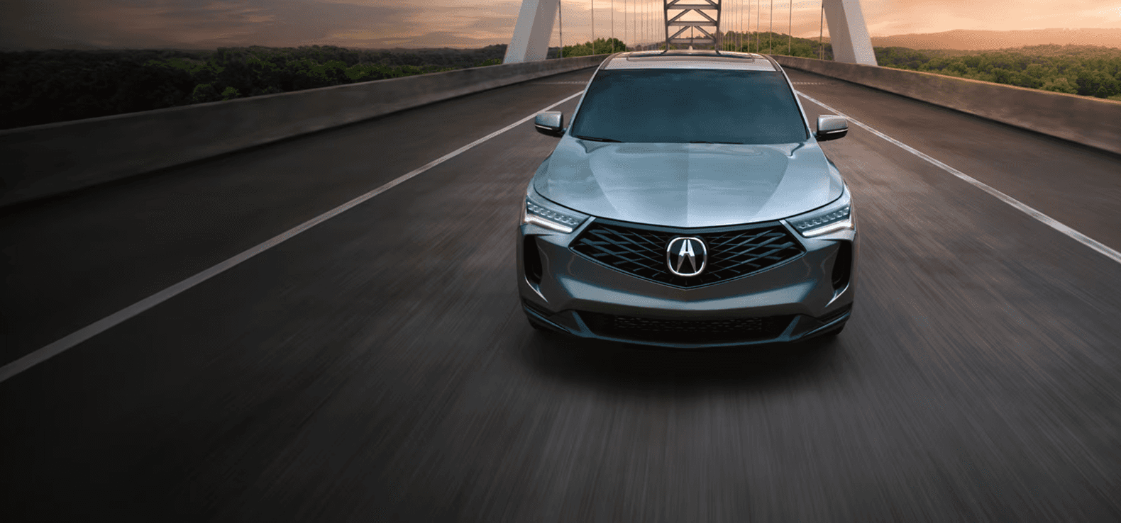 2026 Acura RDX gray front view driving on a bridge at sunset
