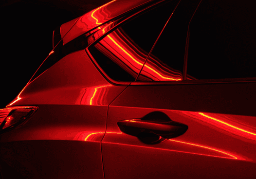 Close-up of red 2026 Acura RDX side panel with reflective lighting