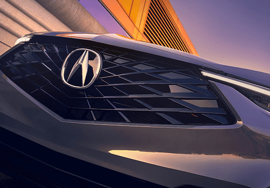Close-up of 2026 Acura ADX front grille and Acura emblem at sunset