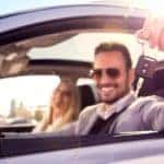 A couple is smiling from the inside of their newly purchased used car.