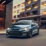 A blue/green 2019 Toyota Corolla is taking a corner on a city street.