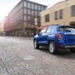 A blue 2017 Chevy Trax, which is popular among used cars in Mesa, is driving on a city street.