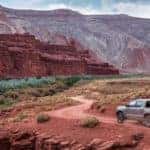 Distant shot of 2019 Toyota Tacoma towing RV in desert with plateaus in background
