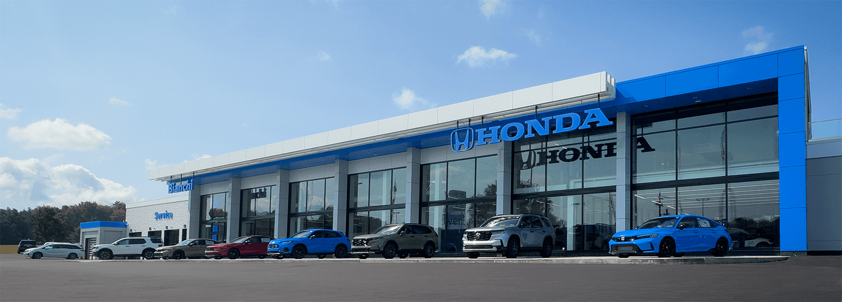 An exterior shot of the Bianchi Honda dealership storefront featuring blue and white architectural elements with a row of cars parked out front on a sunny day.