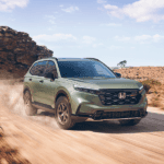 2026 honda cr-v in ash green metallic traveling down a dirt road in the desert during the day