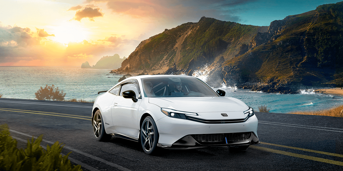 2026 honda prelude in winter frost pearl driving on a road along the coast at sunrise