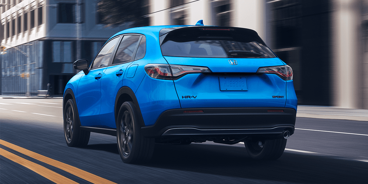 Rear view of 2027 Honda HR-V AWD in Boost Blue Pearl driving in a dark city scape