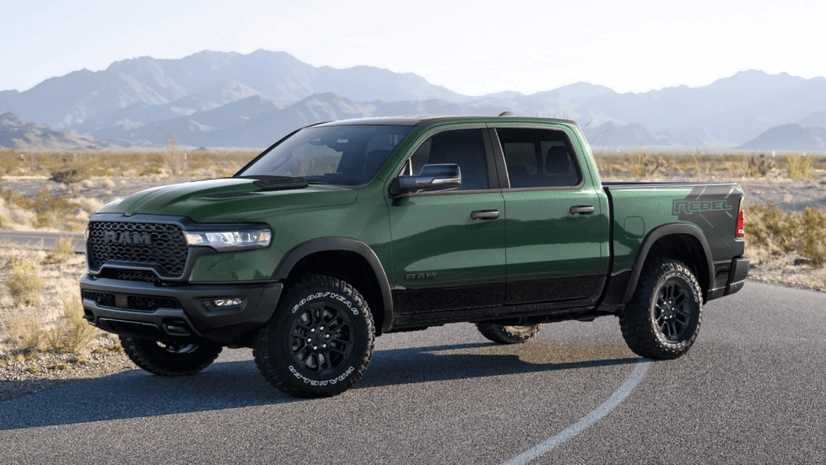 A green RAM 1500 stopped in the middle of the road in a desert