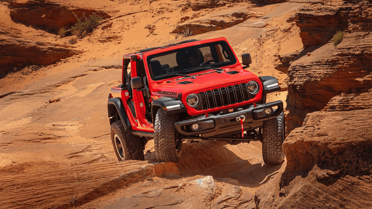 A red Jeep Wrangler driving over rocky terrain
