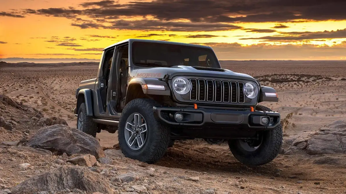 A dark grey Jeep Gladiator driving off-road over rocky terrain in a desert