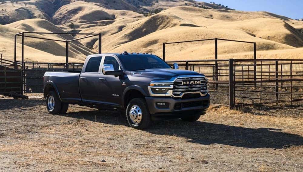A black 2026 Ram 3500 pickup truck parked by a paddock