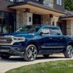 blue 2023 ram 1500 parked on a curved driveway in front of a house