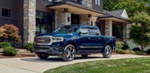 blue 2023 ram 1500 parked on a curved driveway in front of a house