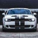 white 2023 dodge challenger with black stripes across the top.