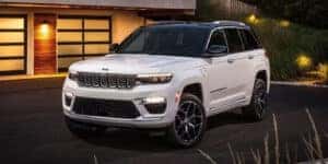white 2024 jeep grand cherokee parked on a driveway in front of a house