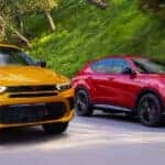 red and yellow 2024 Dodge Hornets driving side by side down a road in a forest area