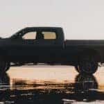 side vide of a man sitting on the trunk of a grey 2024 RAM 2500