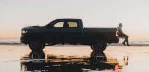 side vide of a man sitting on the trunk of a grey 2024 RAM 2500
