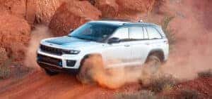 white 2024 jeep grand cherokee off roading driving in a desert