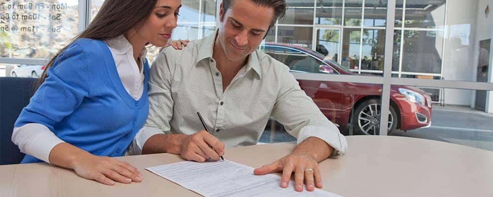 Man and Woman Sign Paperwork at Dealership