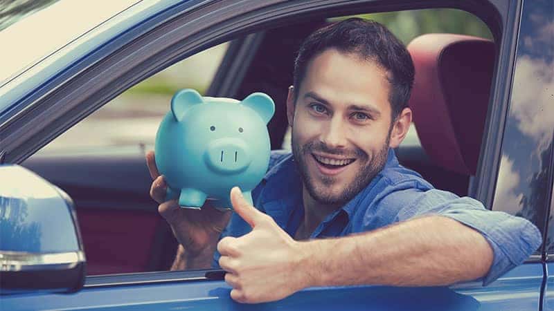 Man gives thumbs up with piggy bank in car
