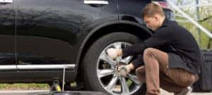 Young man changing tire on side of the road