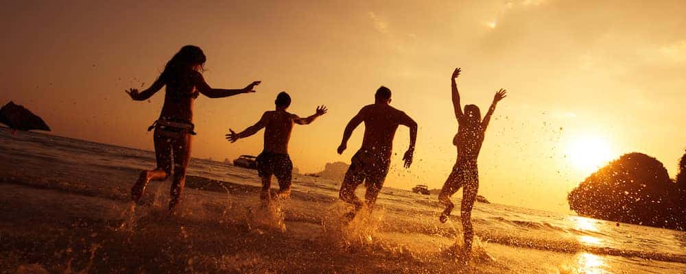 Four friends running into the waves on a beach