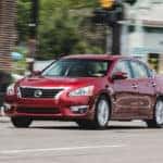 Red Nissan sedan on city street