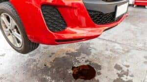 Red car leaking fluid on cement