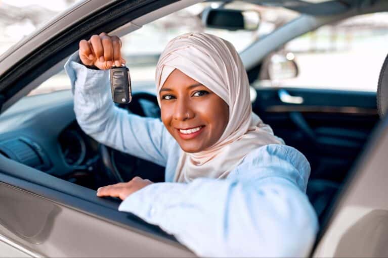 person sitting in car showing car keys