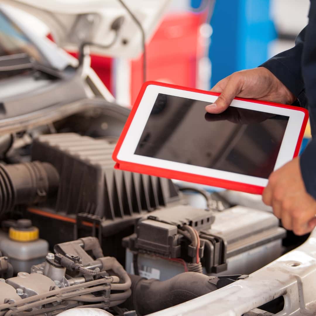Person with tablet looking at a car engine