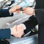 Car dealer handing a customer keys to a new car