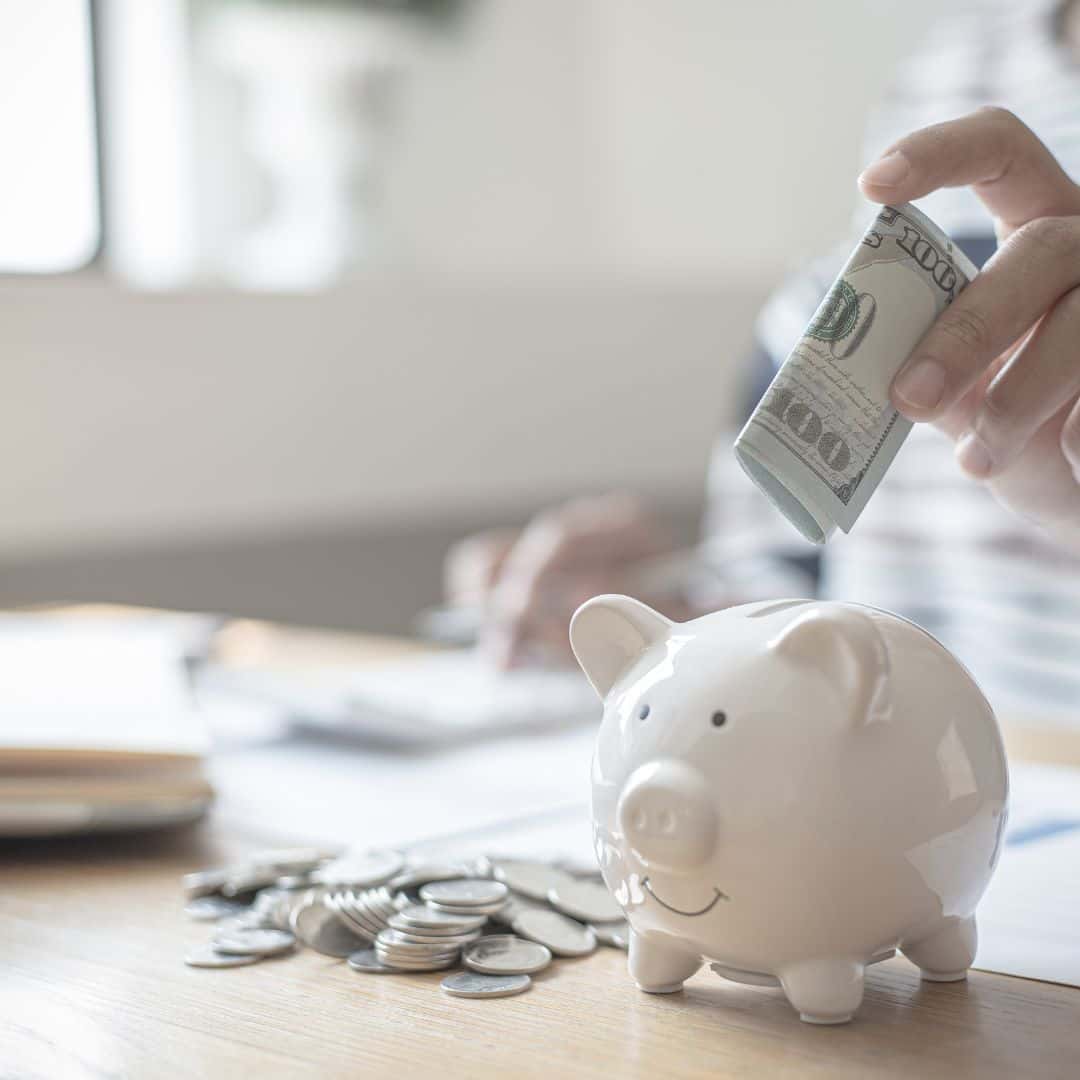 person putting money into a piggy bank