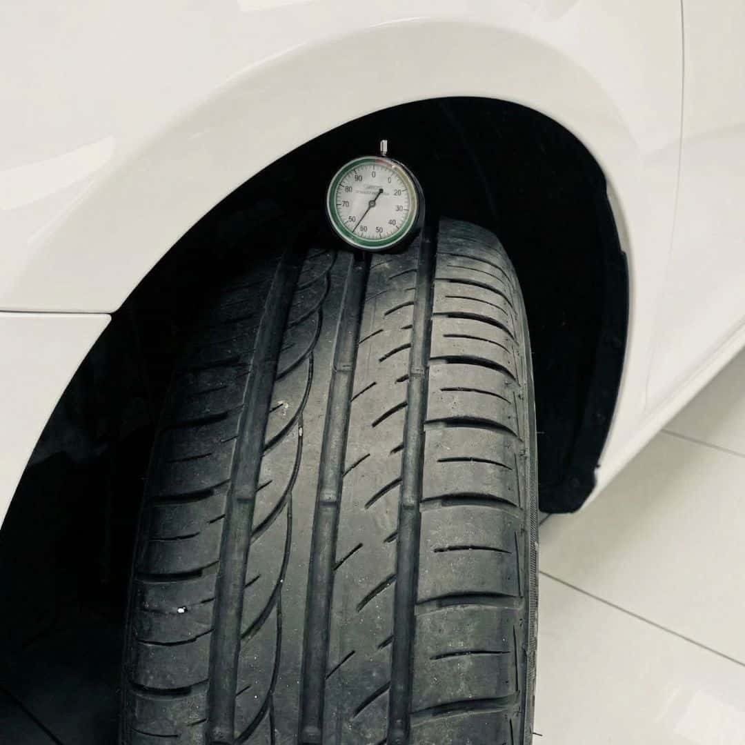 A close-up of a tire tread being checked with a gauge, symbolizing safety inspections.