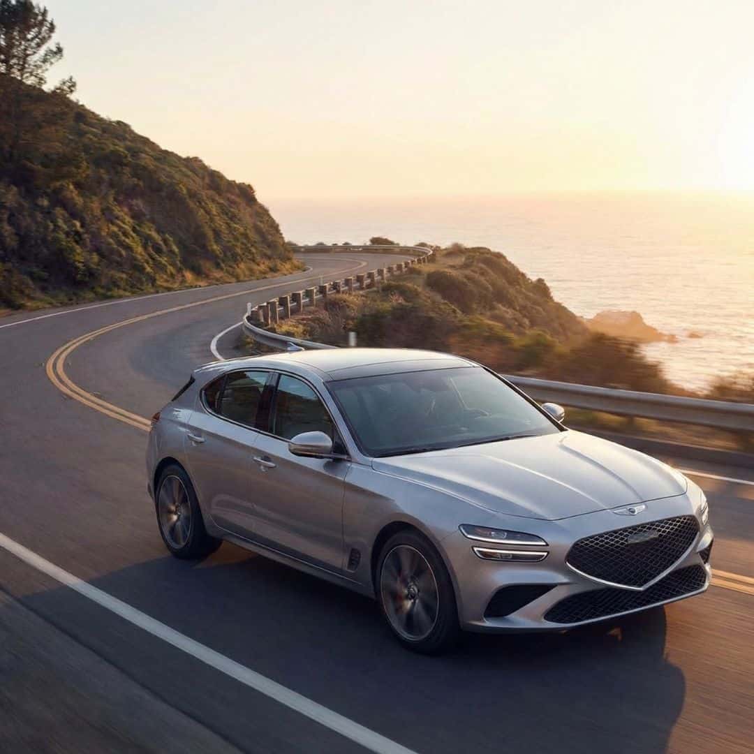 A modern car driving smoothly on a scenic coastal road at sunset, conveying optimal performance.