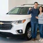 a couple standing next to a new car they bought
