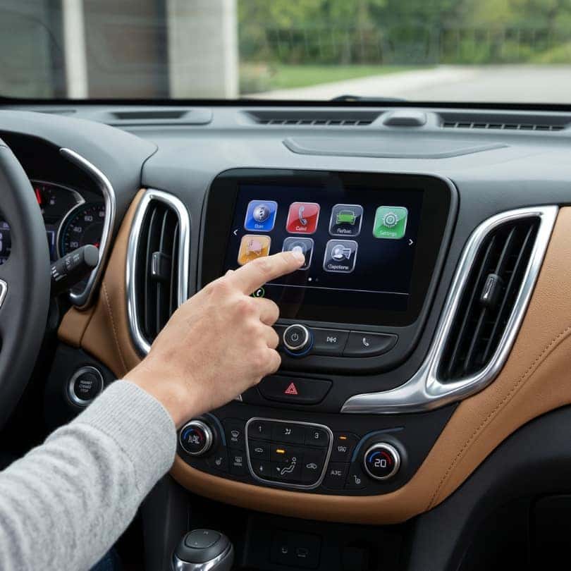 Adjusting the touchscreen display inside a modern Chevrolet Equinox cabin.