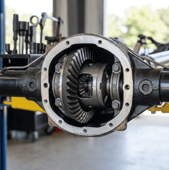 A focused photograph highlights the intricate internal gears of an automatic locking rear differential mechanism within a clean axle housing.