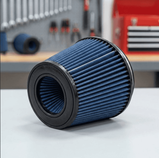 A focused photograph captures the clean, blue filtration media and black end caps of a pristine heavy-duty air filter element resting on a workbench.