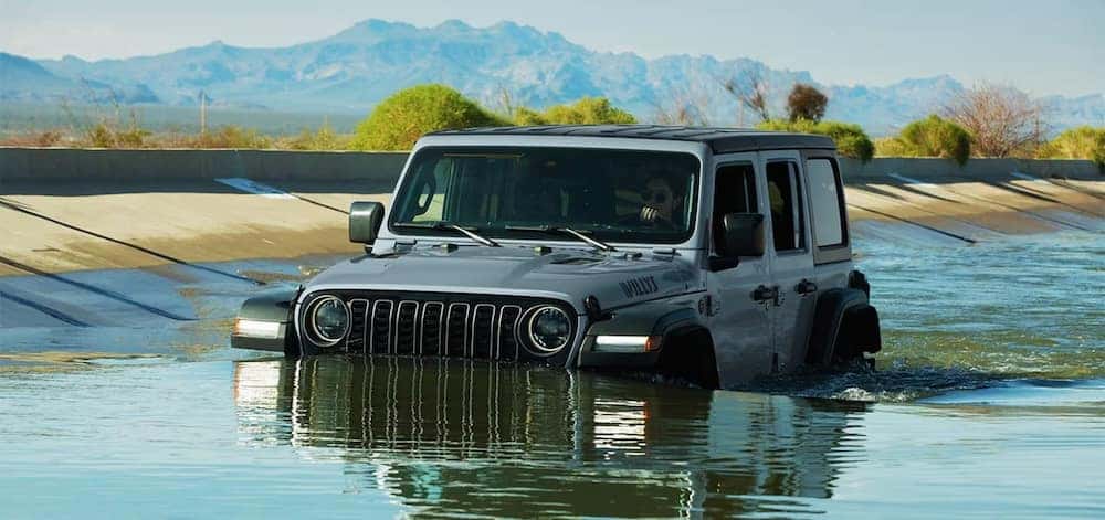 A silver 2026 Jeep Wrangler SUV driving through high water