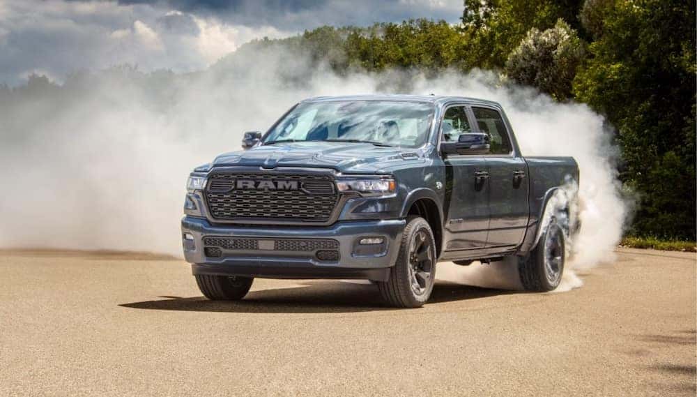 A gray 2026 Ram 1500 pickup truck driving on a dusty dirt road
