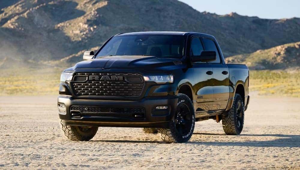 A black 2026 Ram 1500 pickup truck on a dirt road