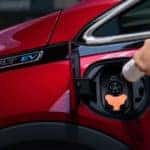 A person charging a red 2020 Chevrolet Bolt EV - El Dorado Chevrolet in McKinney, Texas