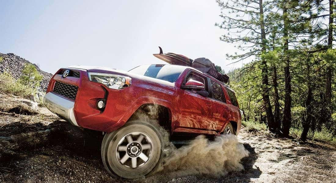 Red Toyota 4Runner side view driving out of woods