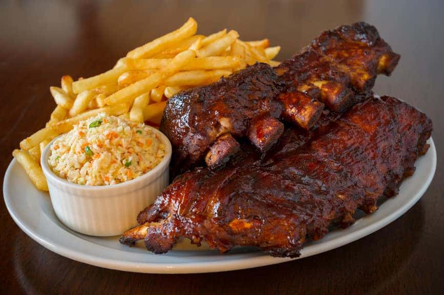 Pork ribs back with french fries and coleslaw salad on the side. Shallow depth of field.